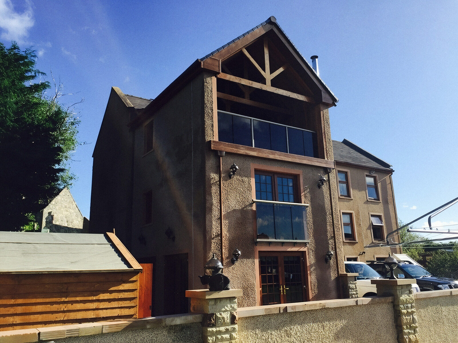 Three-storey stone and timber house with oak gable trusses and glass balconies, built by At Home Construction